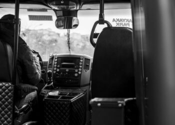 Een buschauffeur achter het stuur van een moderne bus, klaar om passagiers te vervoeren.